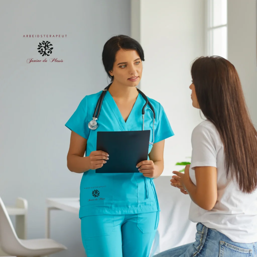 A female healthcare professional in teal scrubs and a stethoscope talking to a female patient in a white t-shirt.