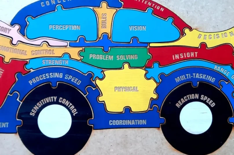 A colorful, car-shaped wooden puzzle with various cognitive, emotional, and physical skills written on its interlocking pieces.