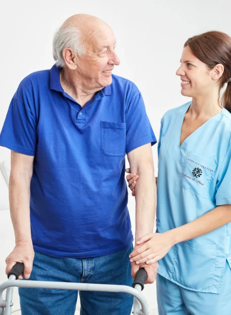 A smiling elderly man using a walker assisted by a female occupational therapist.